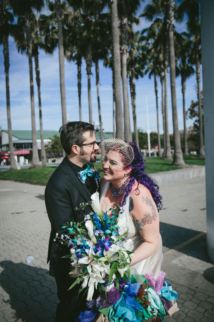 Creative wedding couple laughing in Jack London Square with palm trees in background by Becca Henry