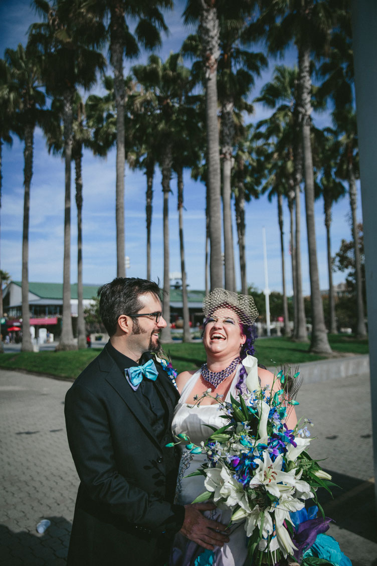 Creative wedding couple laughing in Jack London Square with palm trees in background by Becca Henry