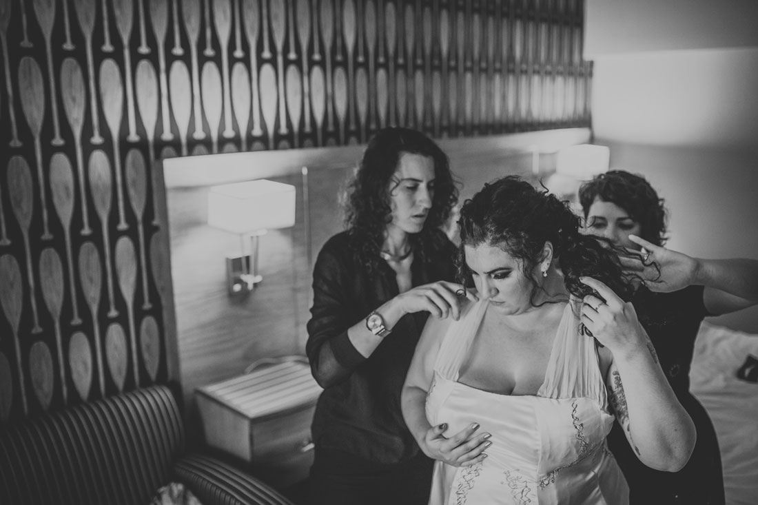 Bride putting on her dress with rad purple hair at Waterfront Hotel by Becca Henry Photography.