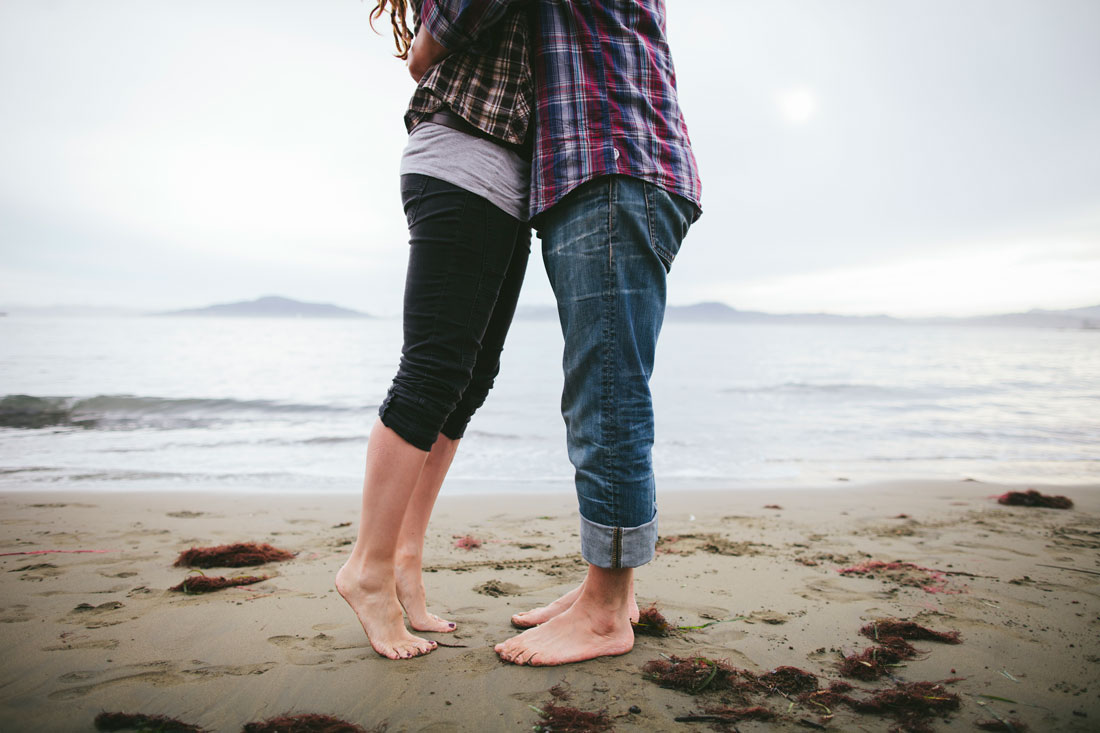 California casual engagement session- couple on tippy toes kissing on the beach by Becca Henry Photography