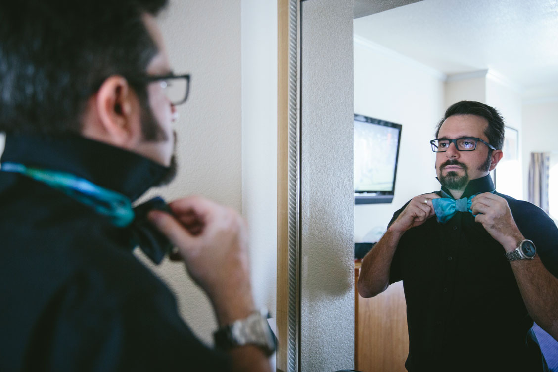 Groom straightening turquoise tie getting ready for the wedding by Becca Henry Photography