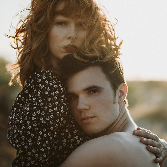 Romantic couple embracing at sunset in Palm Springs, bathed in golden light—capturing intimate love and dreamy desert vibes.