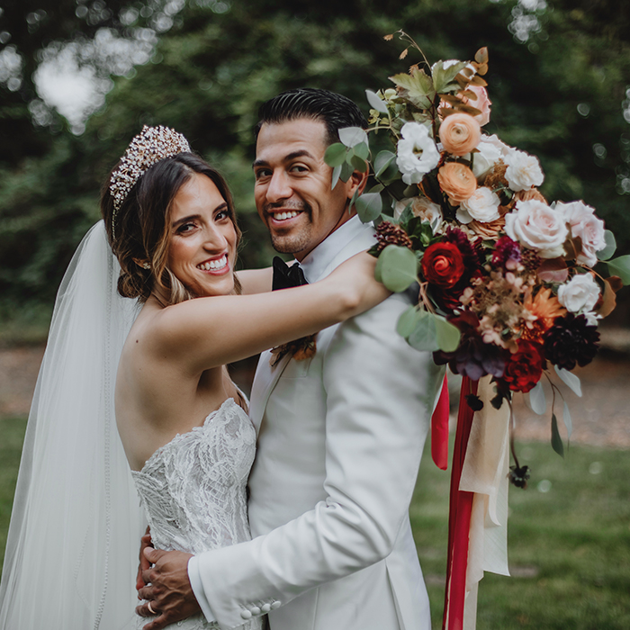 St Helena Elegant vineyard wedding – A joyful bride throws her arms around the groom as she holds a gorgeous bouquet, capturing a romantic and timeless celebration.