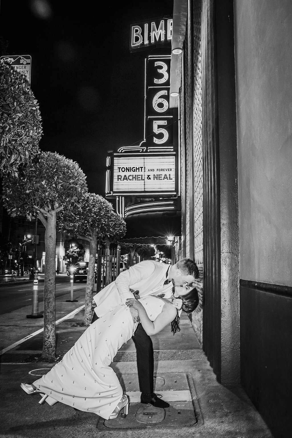 Couple kissing on city sidewalk at night for branding photography.