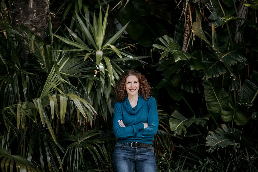 Woman smiling in front of lush green tropical plants for branding.