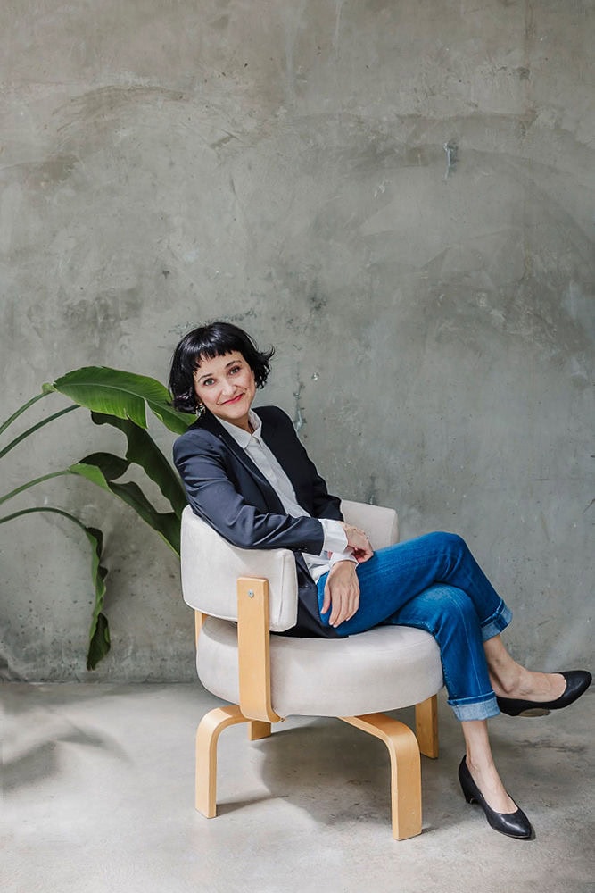 Professional woman in business attire sitting on a modern chair.