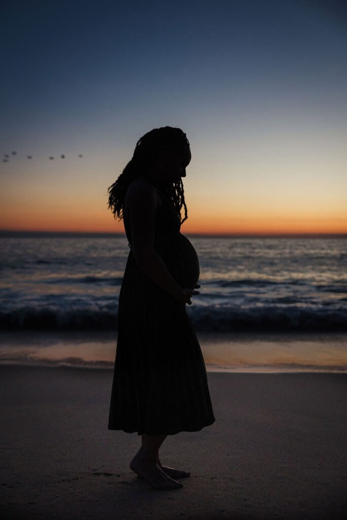 Silhouette of pregnant woman on beach at sunset for branding.